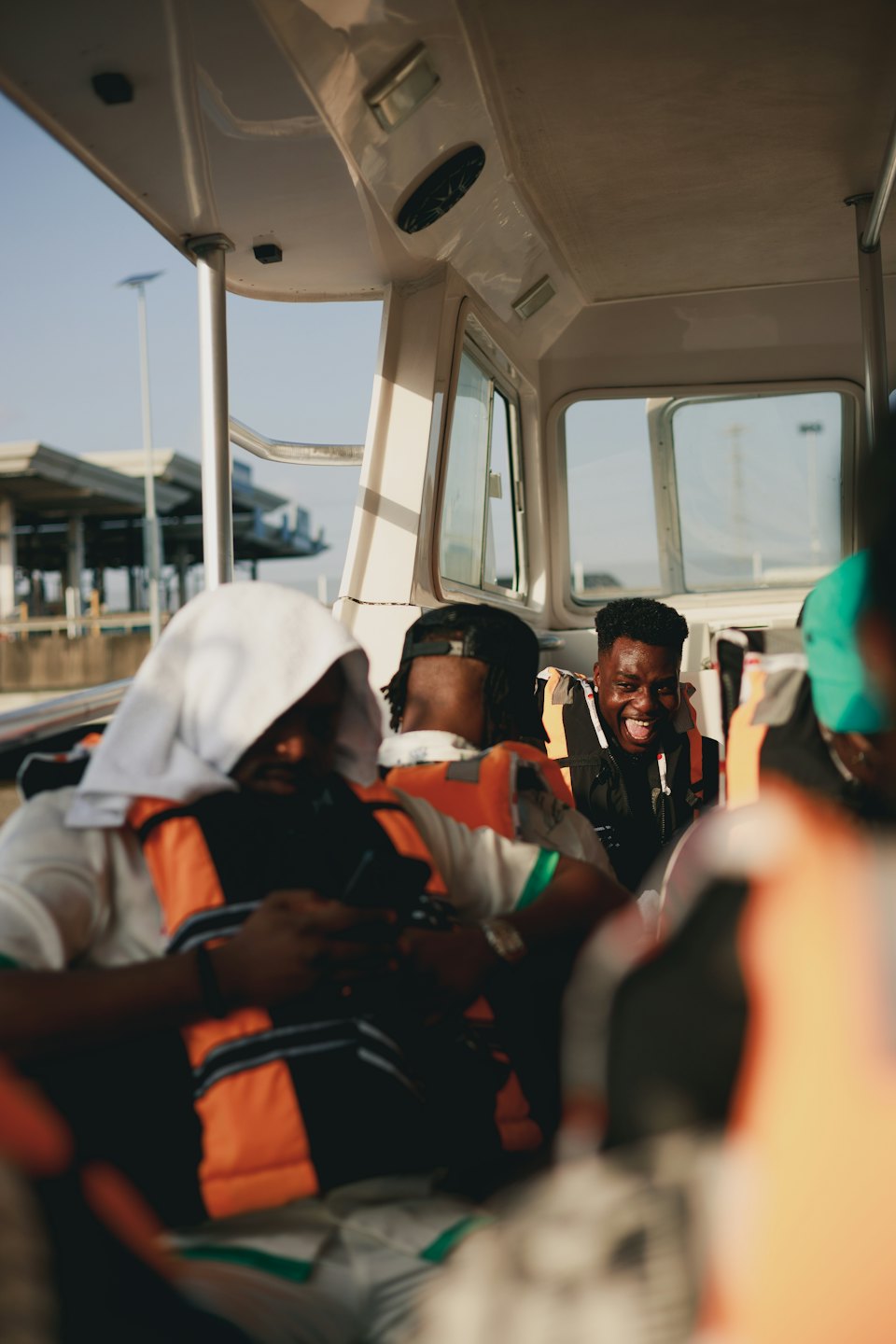 People wearing orange life vests laugh during a boat ride.
